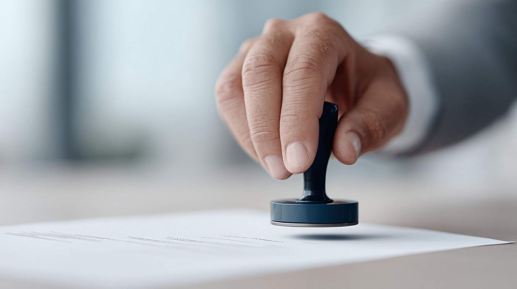 Eine Hand mit einem Stempel positioniert über einem Stück Papier.
